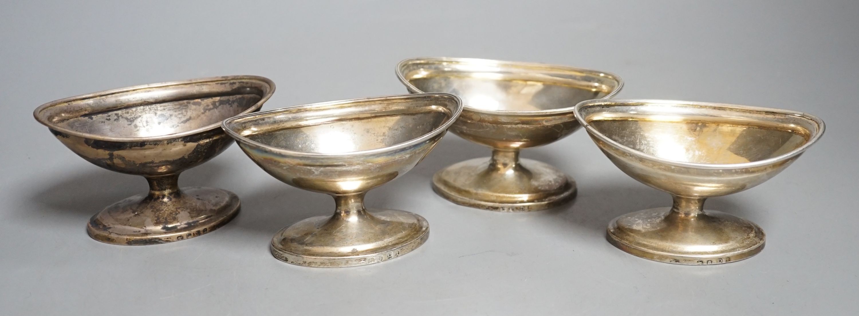 A set of four George III silver boat shaped pedestal salts, London, 1799, maker's mark rubbed, length 10cm, 345 grams.